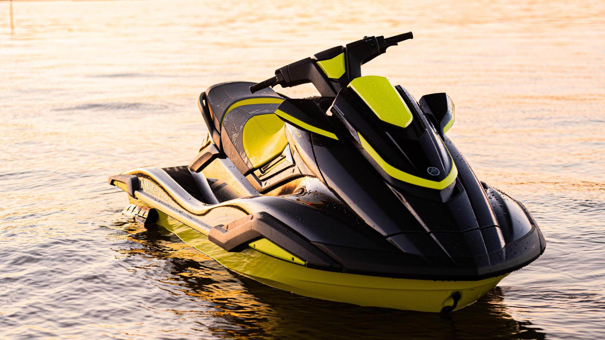 A yellow and black jet ski idle in the water with no one riding it