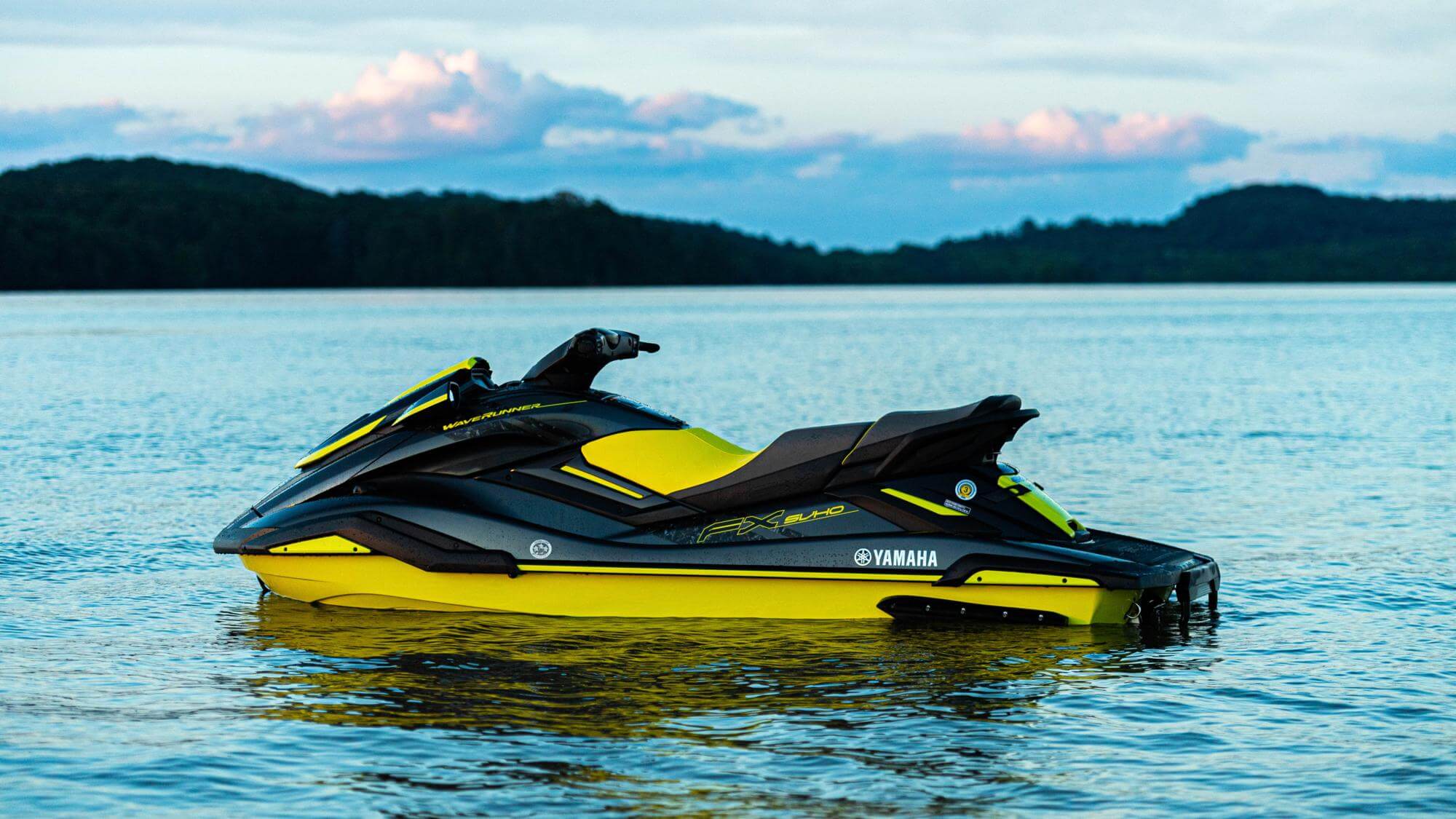 a yellow and black jet ski sat in the water with no one riding on it