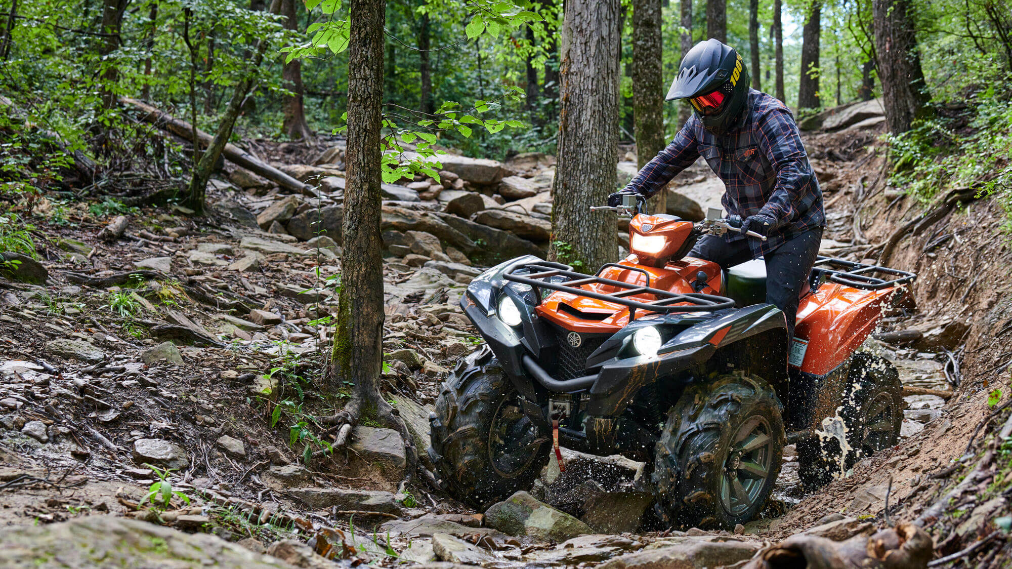 Person on a orange quad bike in the woods surrounded by trees